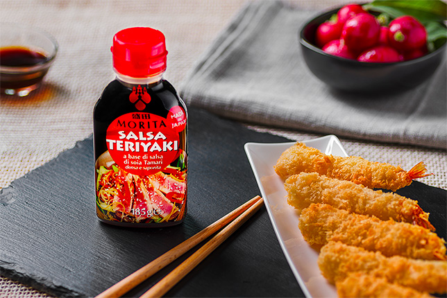 La boccetta di salsa Teriyaki Morita a lato di un piatto di tempura di gamberi.